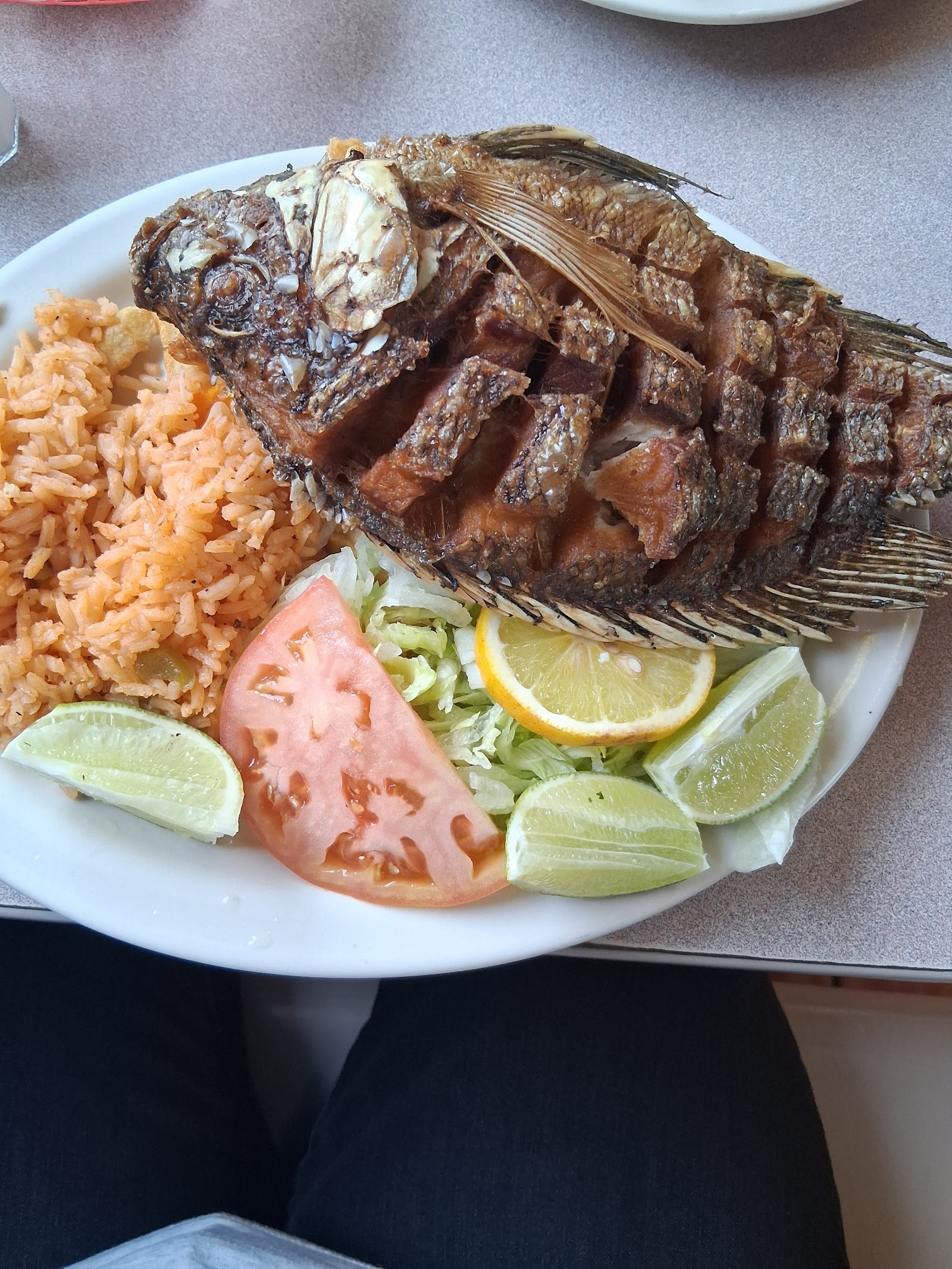 Whole fried mojarra fish plate with rice and salad